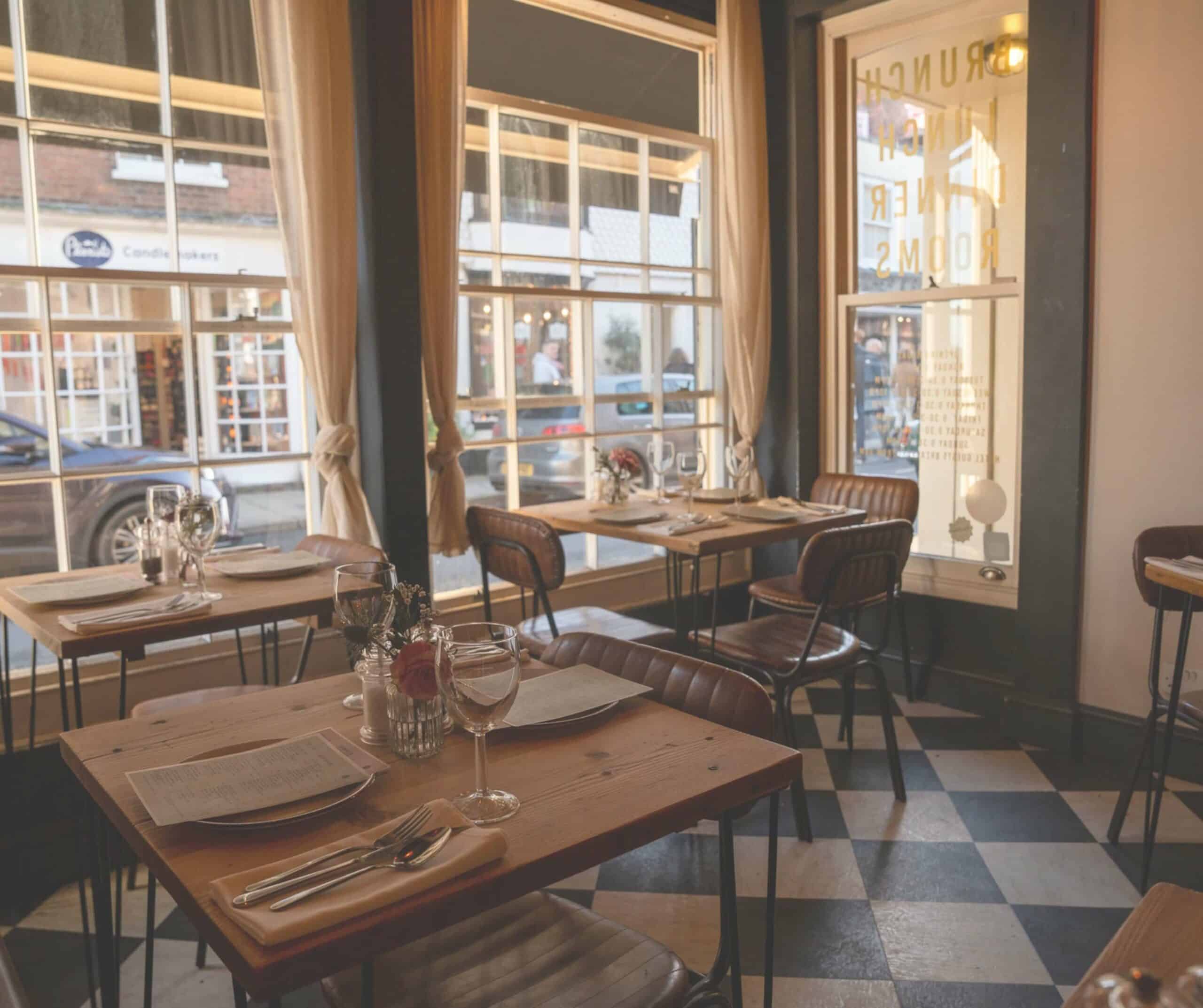 Interior of The Fig restaurant in Rye with wooden tables, leather chairs, and a checkered floor by the front windows