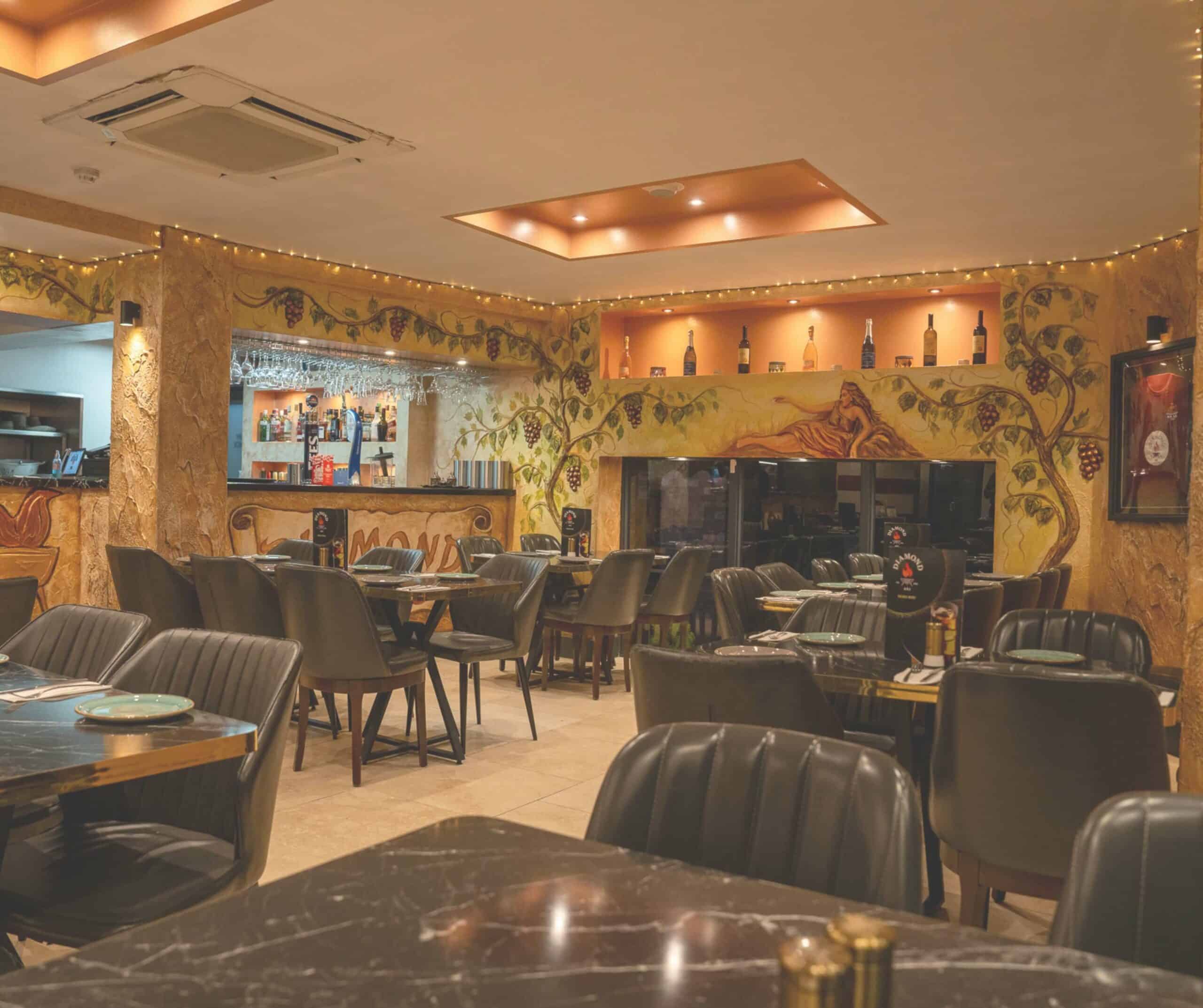 Interior of Diamond Köz Turkish restaurant in Rye with grape-vine murals, a bar, leather chairs, and marble tables