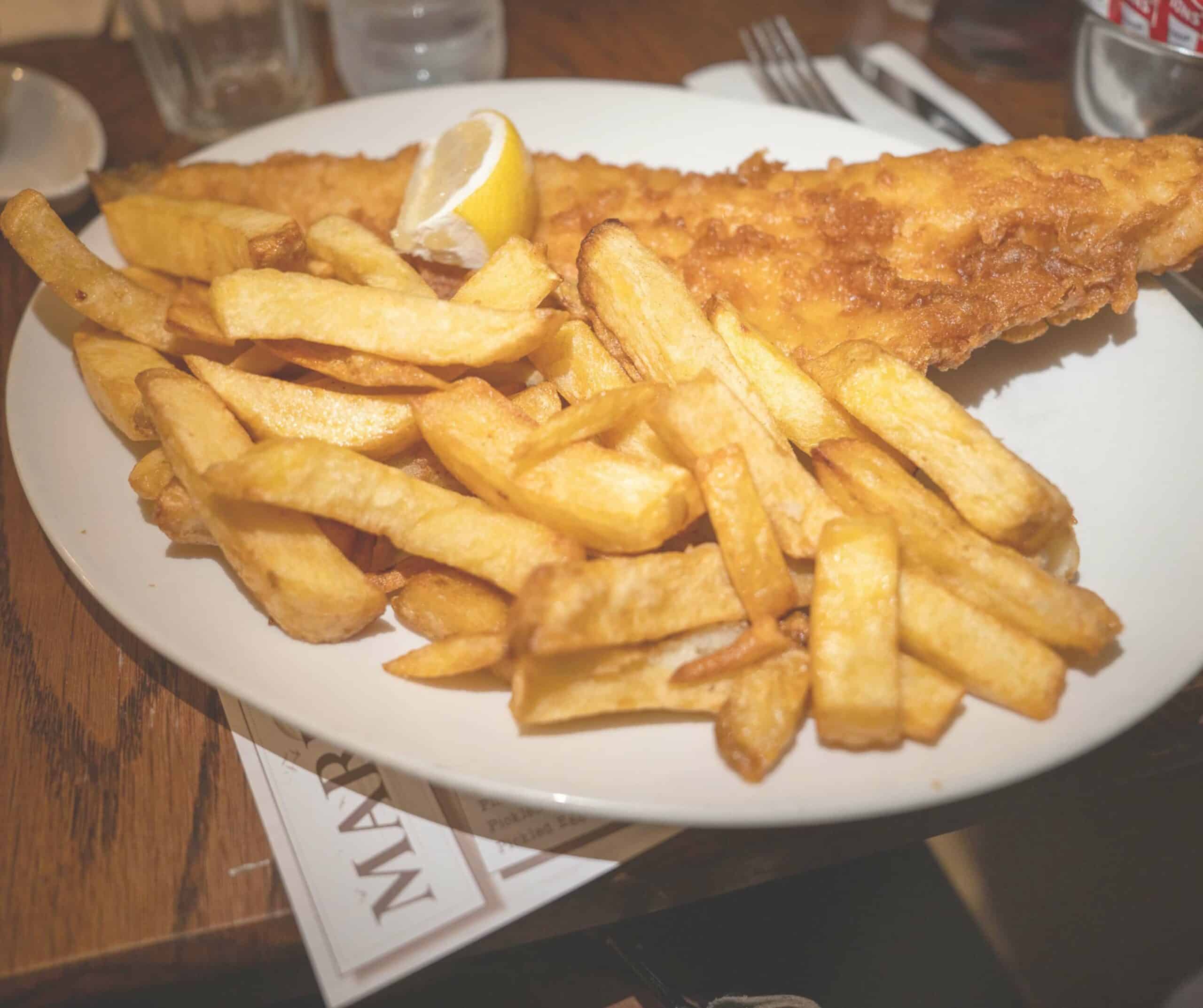 Large cod and chips at Marino's Fish Bar in Rye with golden battered fish, thick-cut chips, and a lemon wedge on a white plate