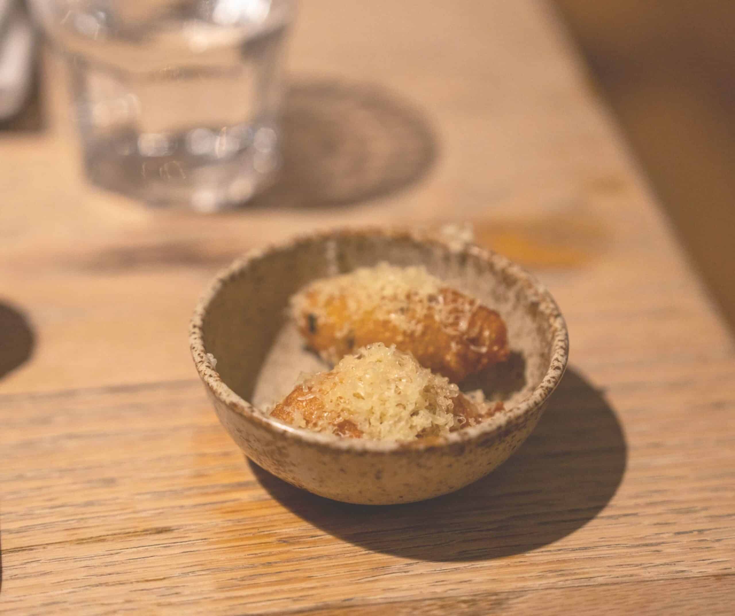 Savory beignets topped with grated cheese in a small ceramic bowl at The Union in Rye