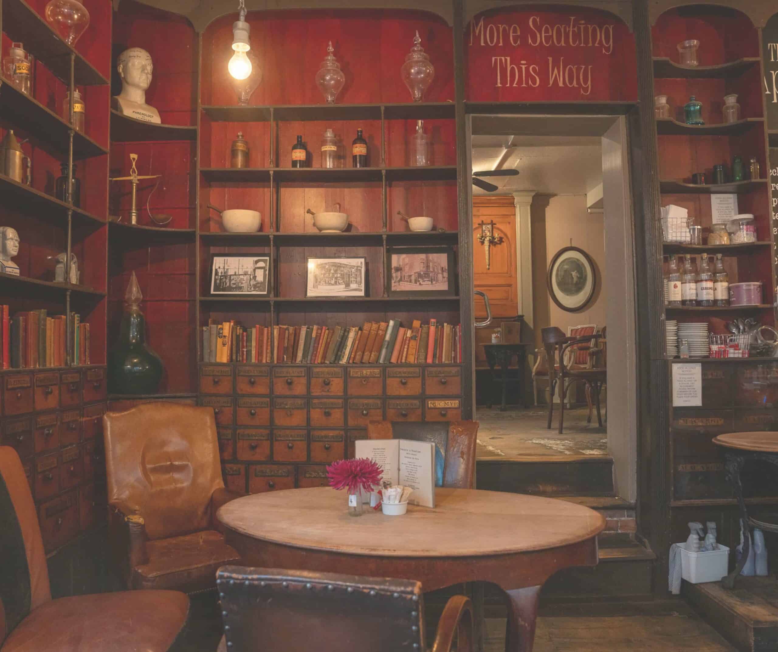 Vintage apothecary interior at the Apothecary Coffee House in Rye with old medicine drawers, glass bottles, and leather chairs