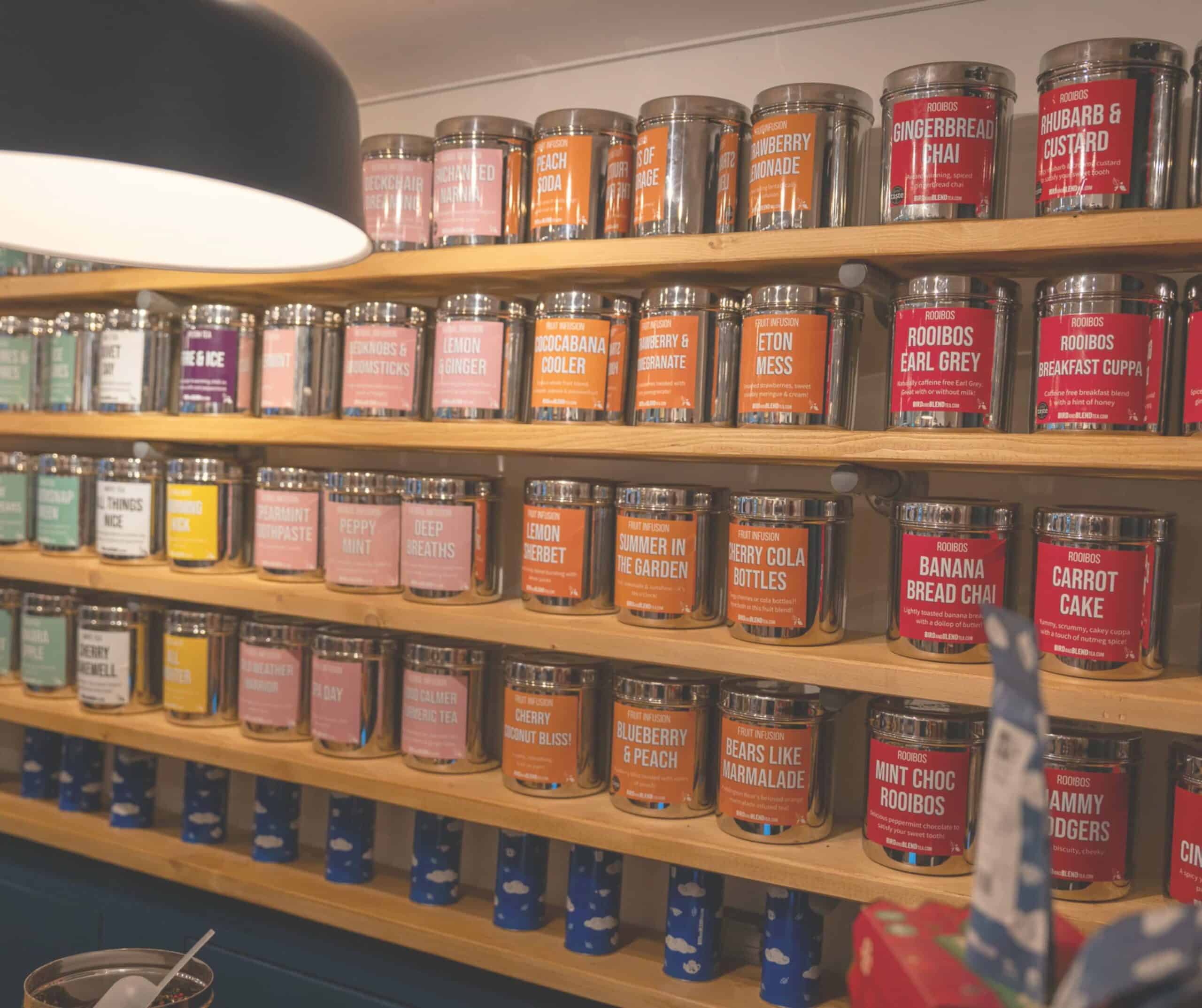 Bird & Blend tea wall in Rye lined with colorful tins of blends like Eton Mess, Carrot Cake, and Rooibos Earl Grey