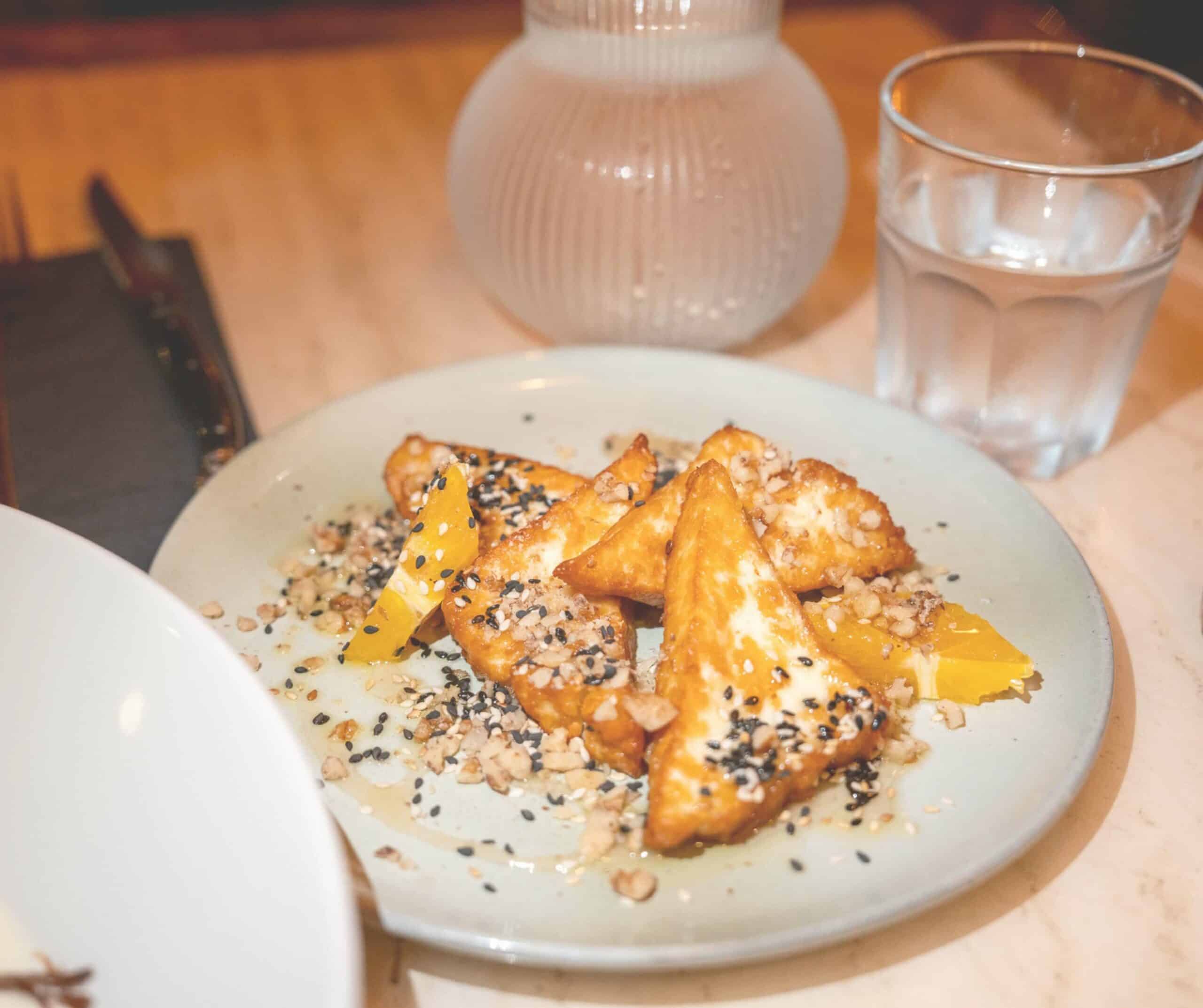 Fried halloumi with orange, sesame seeds, and crushed nuts on a blue plate at Marco's Mediterranean Kitchen in Rye