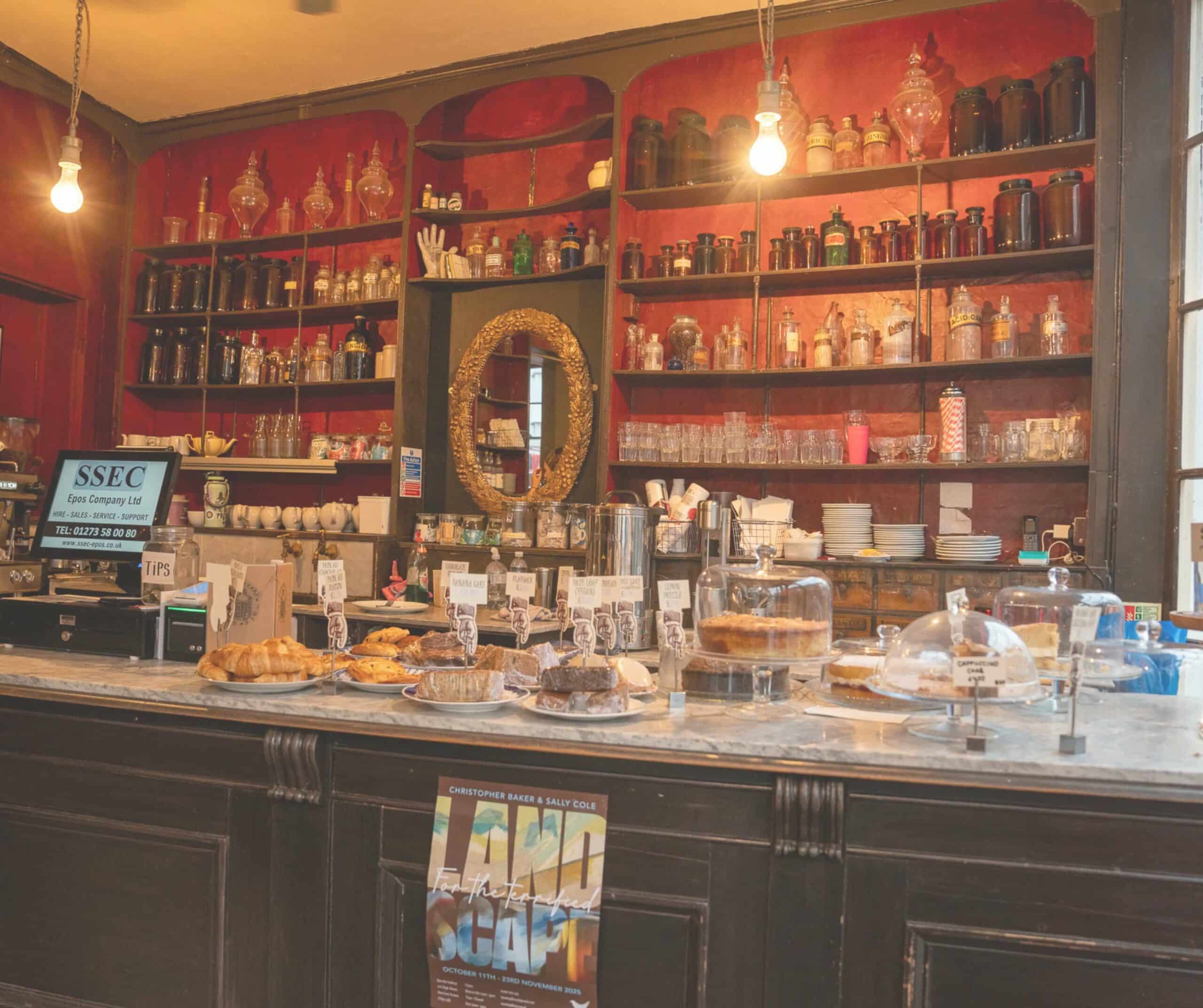Cake and pastry counter at the Apothecary Coffee House in Rye, with antique glass jars on deep red shelves behind