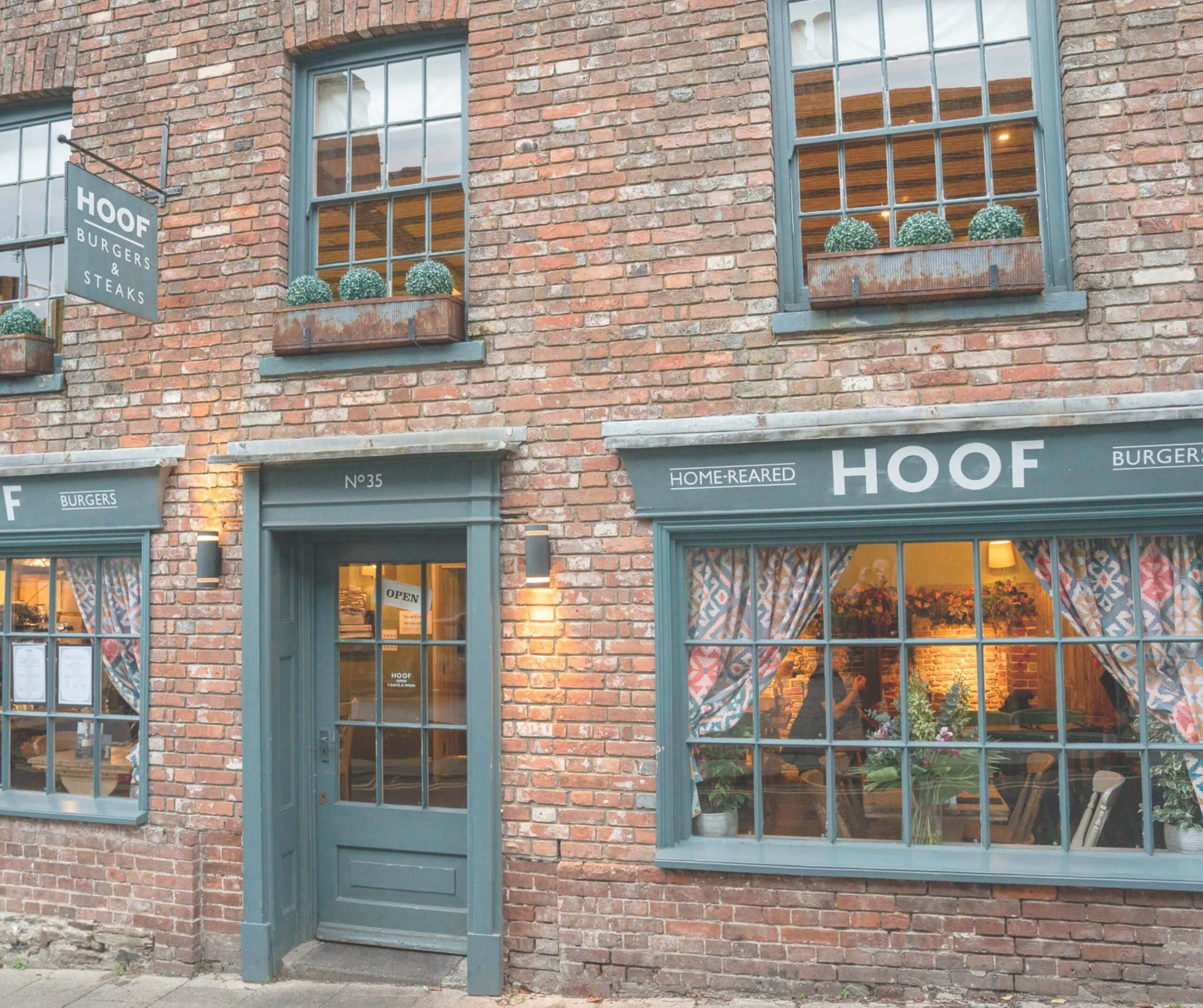 Exterior of Hoof burgers and steaks restaurant at No 35 The Mint in Rye, East Sussex, a brick building with teal-green window frames