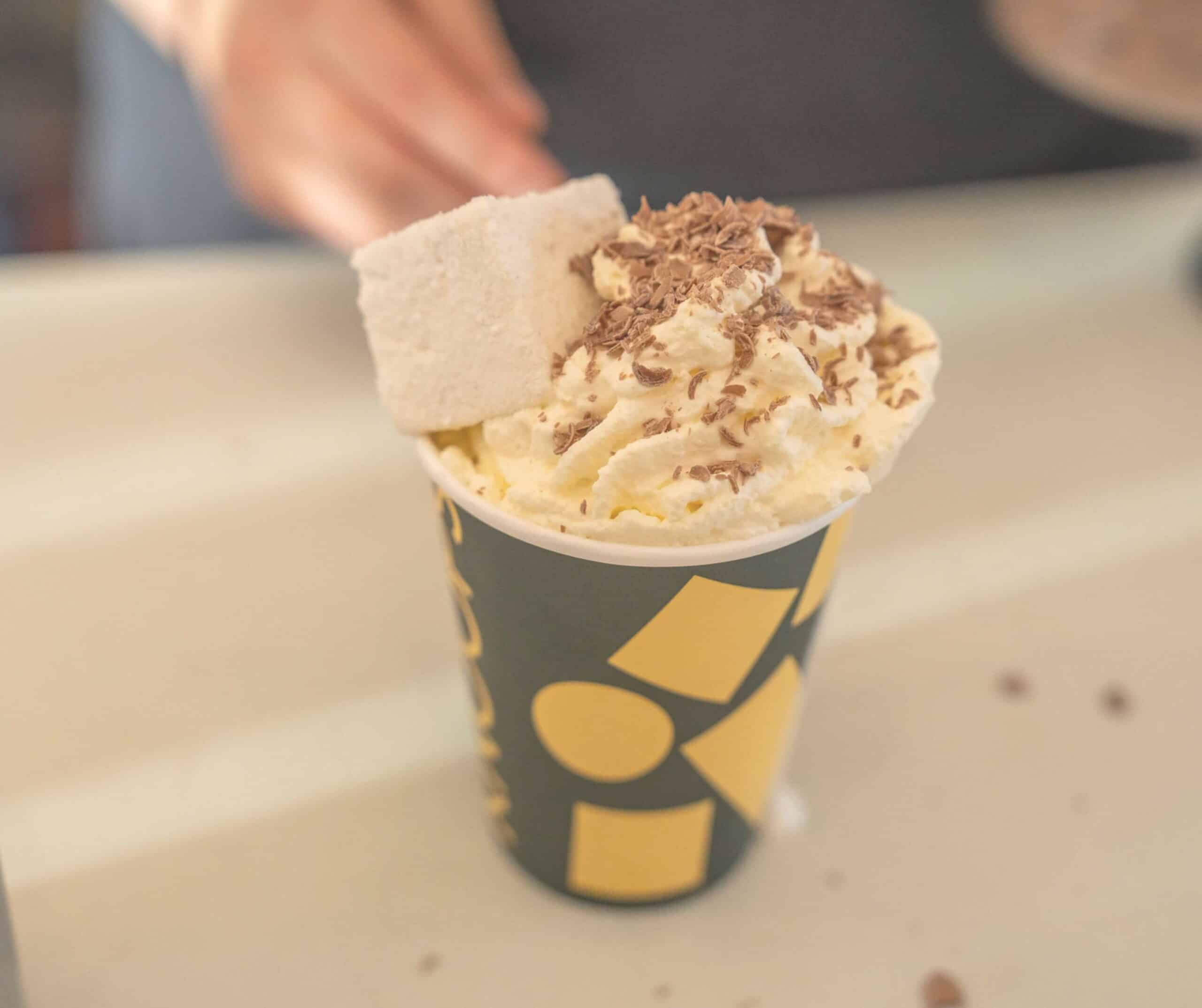 Knoops hot chocolate in Rye topped with whipped cream, chocolate shavings, and a handmade marshmallow in a branded cup