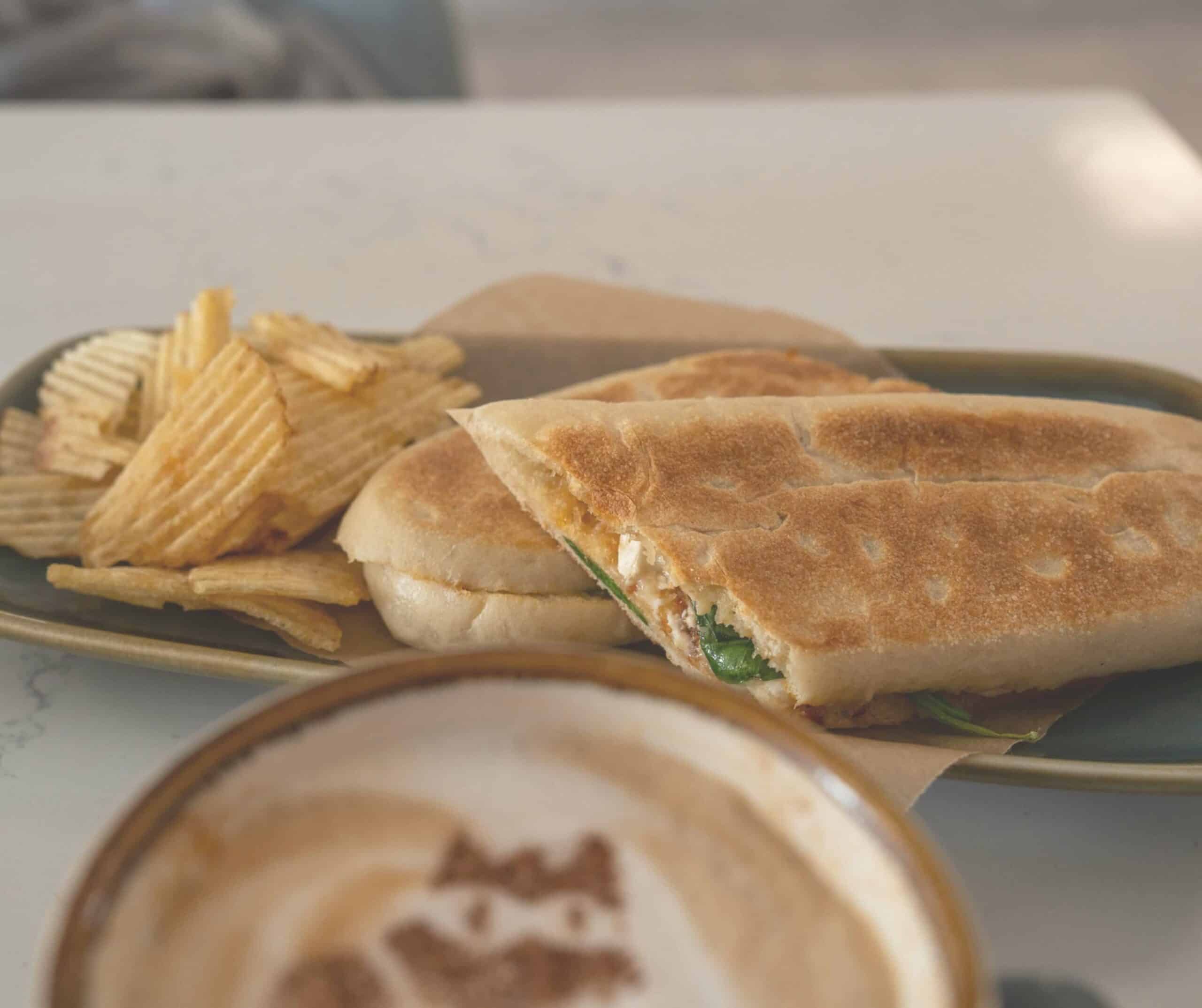 Toasted panini with ripple chips and a cat-art cappuccino at Kiko's Cat Cafe in Rye