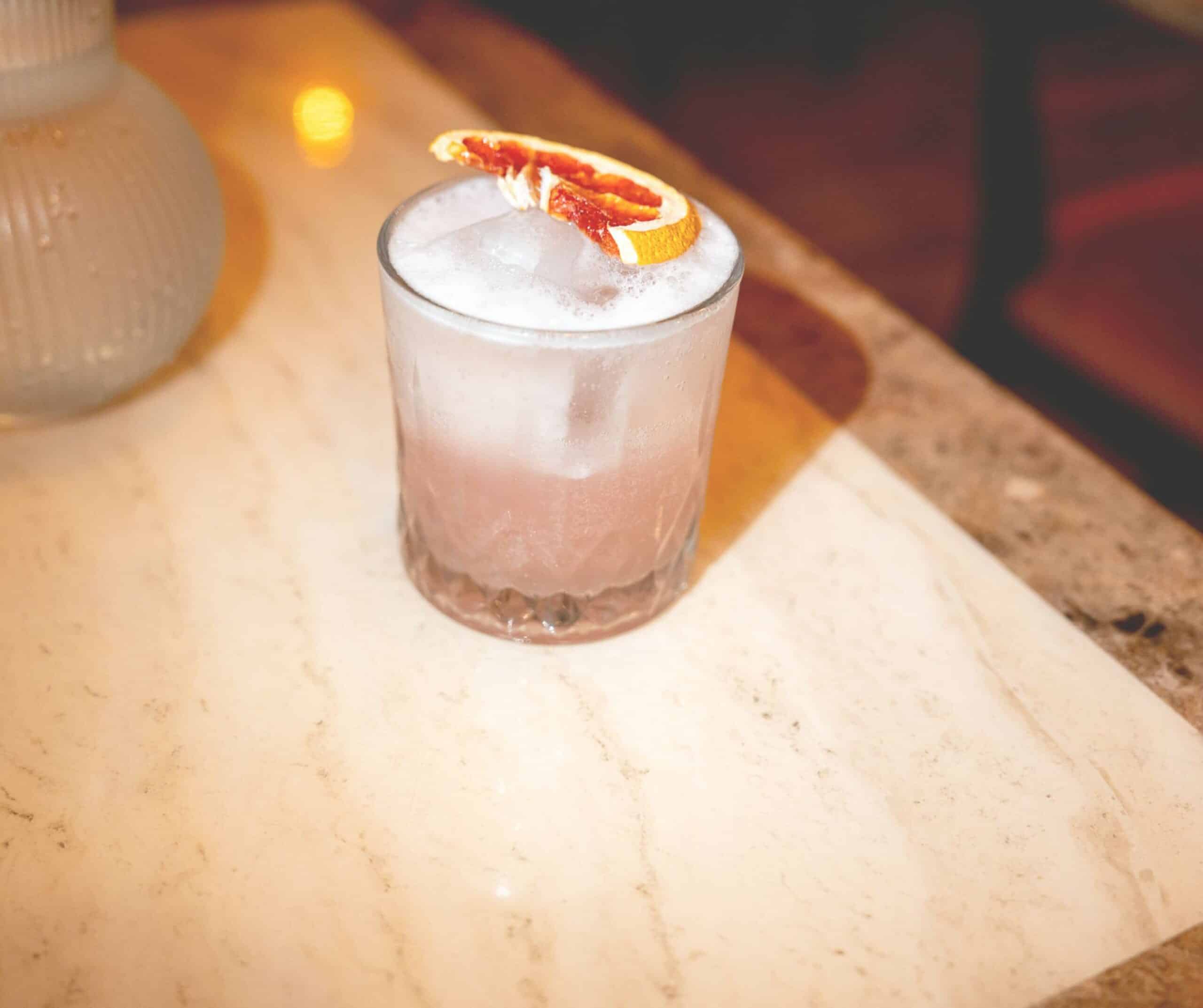 Cocktail with foam and a dried orange slice in a tumbler at Marco's Mediterranean Kitchen in Rye