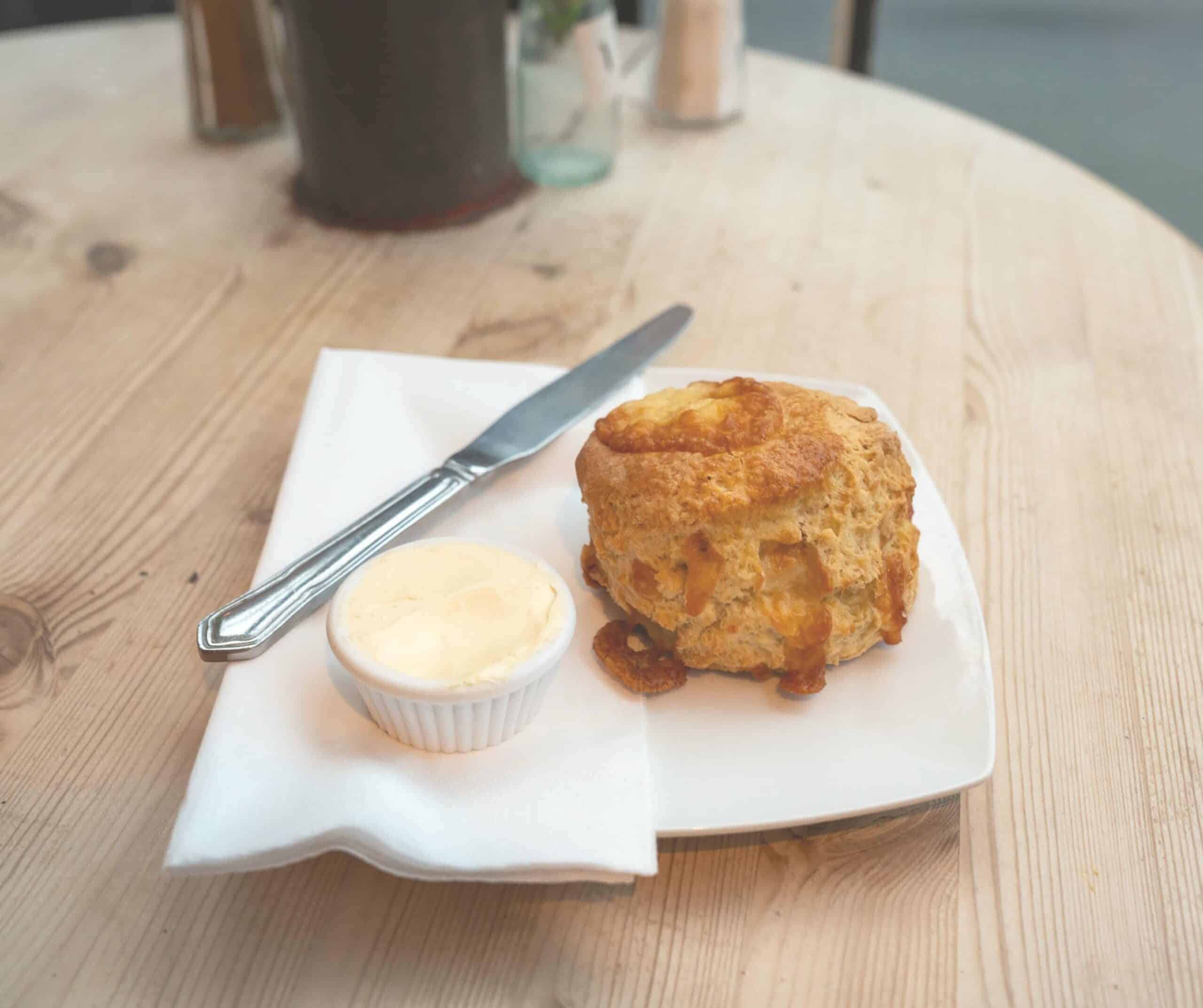 Cheese scone with a pot of butter on a white plate at the Apothecary Coffee House in Rye