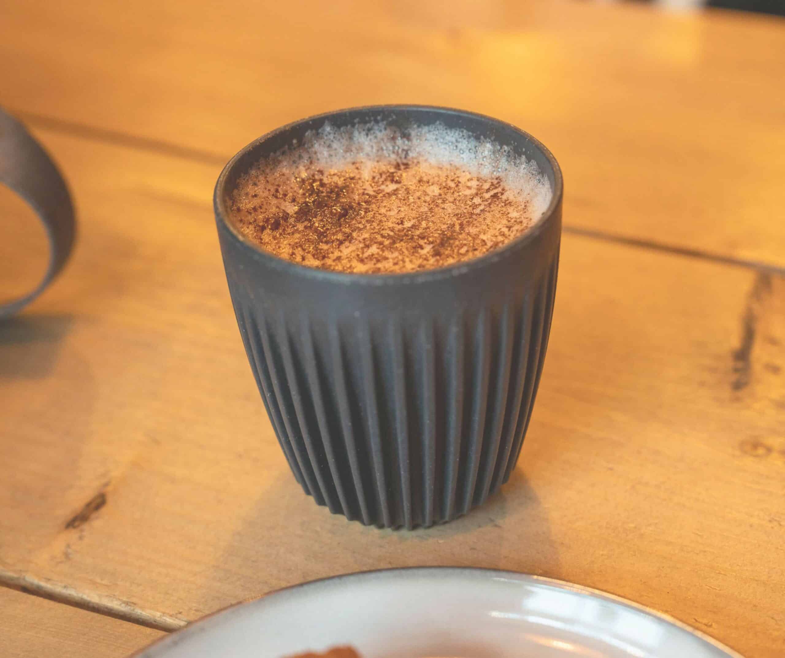 Cappuccino dusted with cinnamon in a ribbed cup at Grounded cafe in Rye