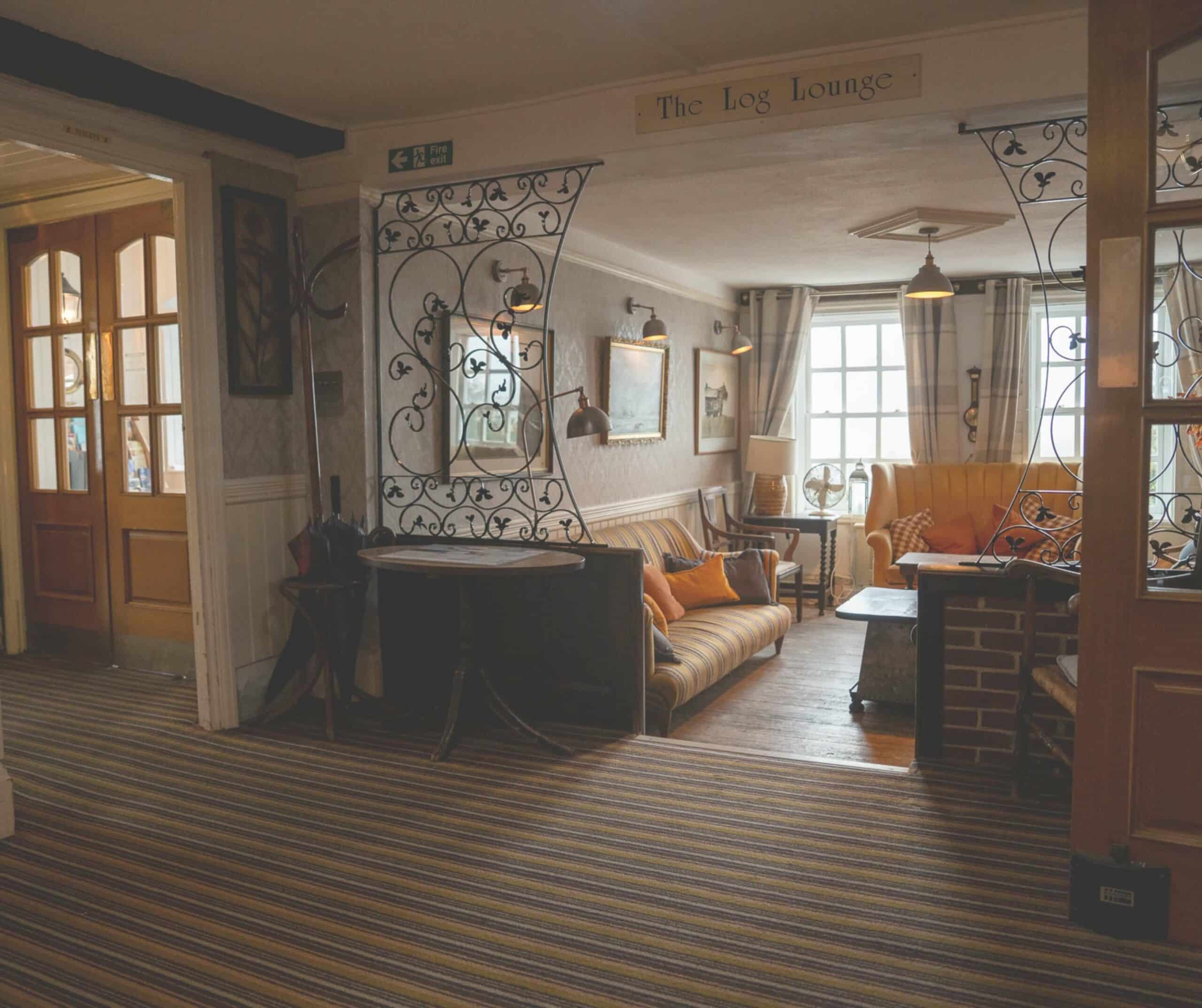 The Log Lounge at the Hope Anchor Hotel in Rye with striped sofas, antique furniture, and wrought iron details