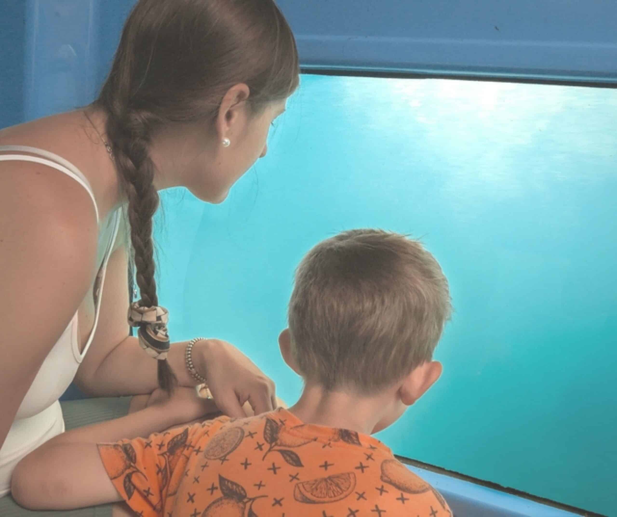Woman and young boy looking through the underwater viewing window of a glass-bottom boat